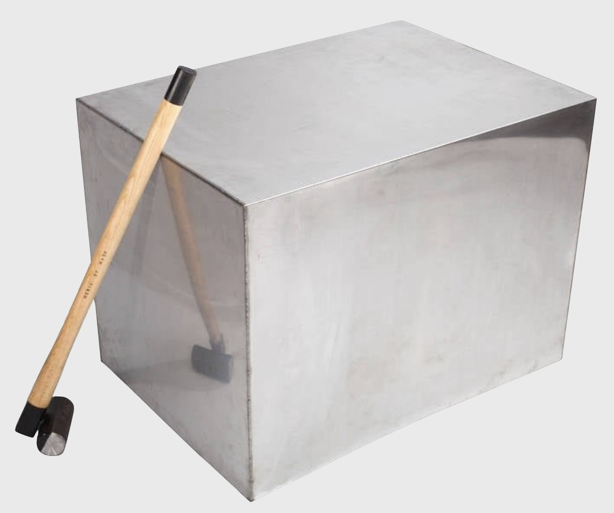 Glänzender Metallwürfel mit einem Holzstielhammer, der dagegen lehnt.